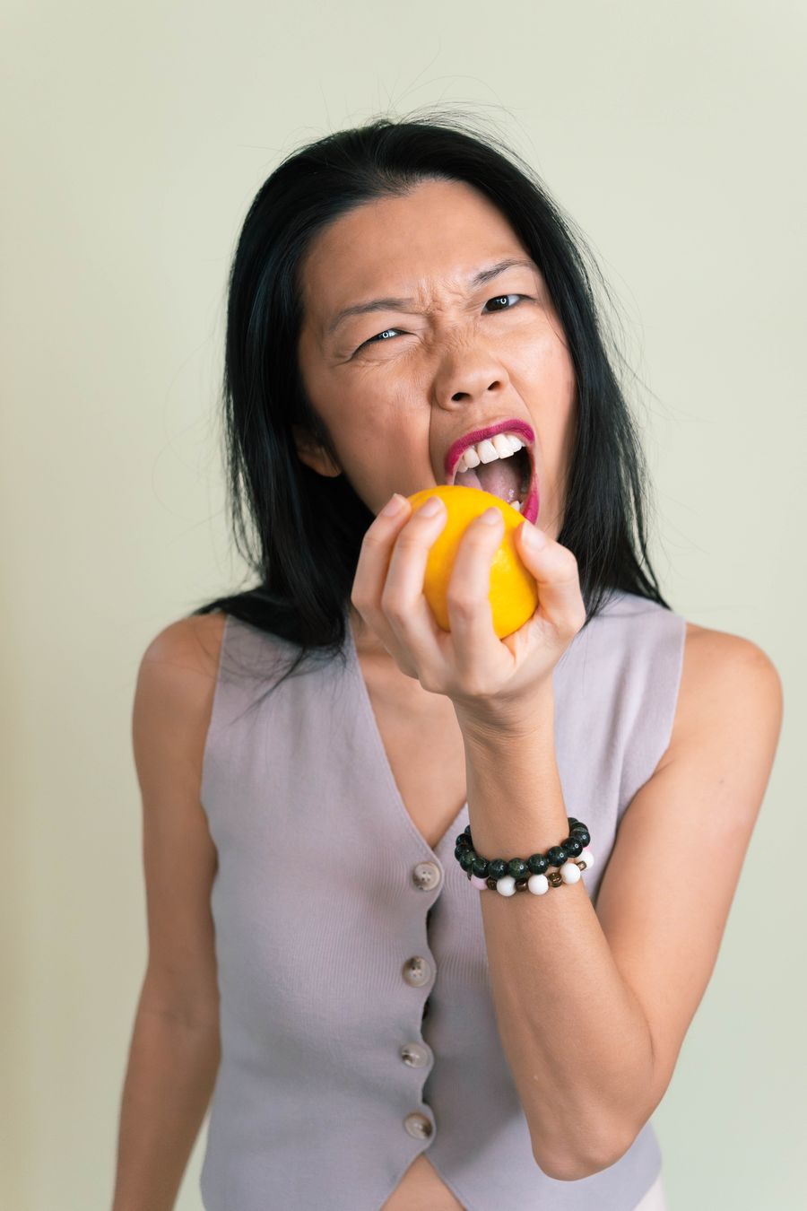 Tammie pulling a face as she bites into a whole lemon