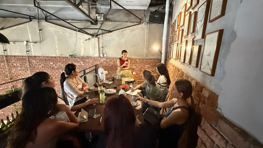 Women gathered around a long table in a warm, brick-walled room